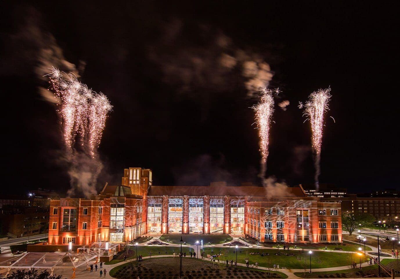 Fireworks illuminate a grand building against the night sky.