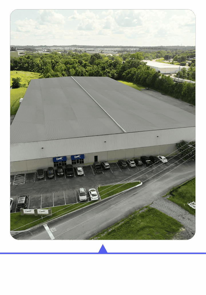 A large warehouse with trucks parked outside on a sunny day.